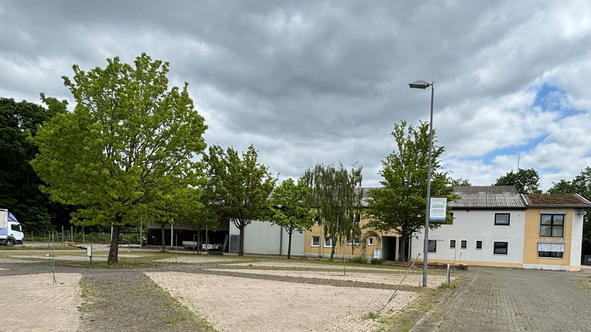 Auf dem Bild ist ein Teil des Zirener-Grundstücks mit Bäumen und dem Bürogebäude zu sehen.