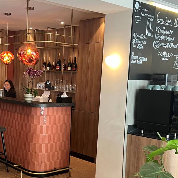 Eine Frau steht hinter der Rezeption im Eingangsbereich eines Hotels.