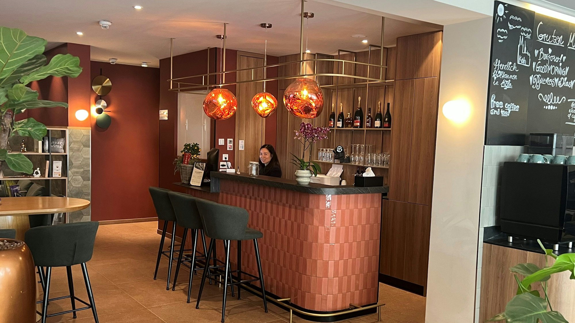 Eine Frau steht hinter der Rezeption im Eingangsbereich eines Hotels.