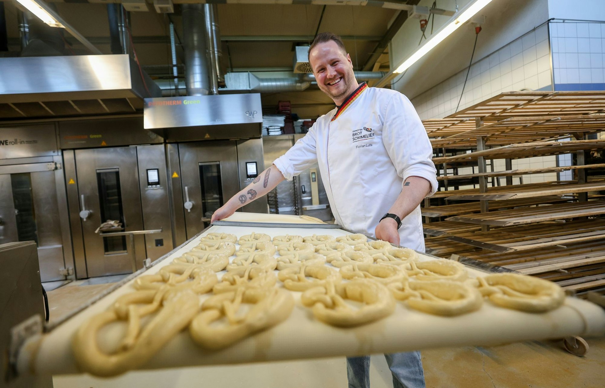 Backen ist Kunst: Brot-Sommelier Florian Lutz steht in seiner Backstube und schiebt ein Blech Brezeln in den Ofen.