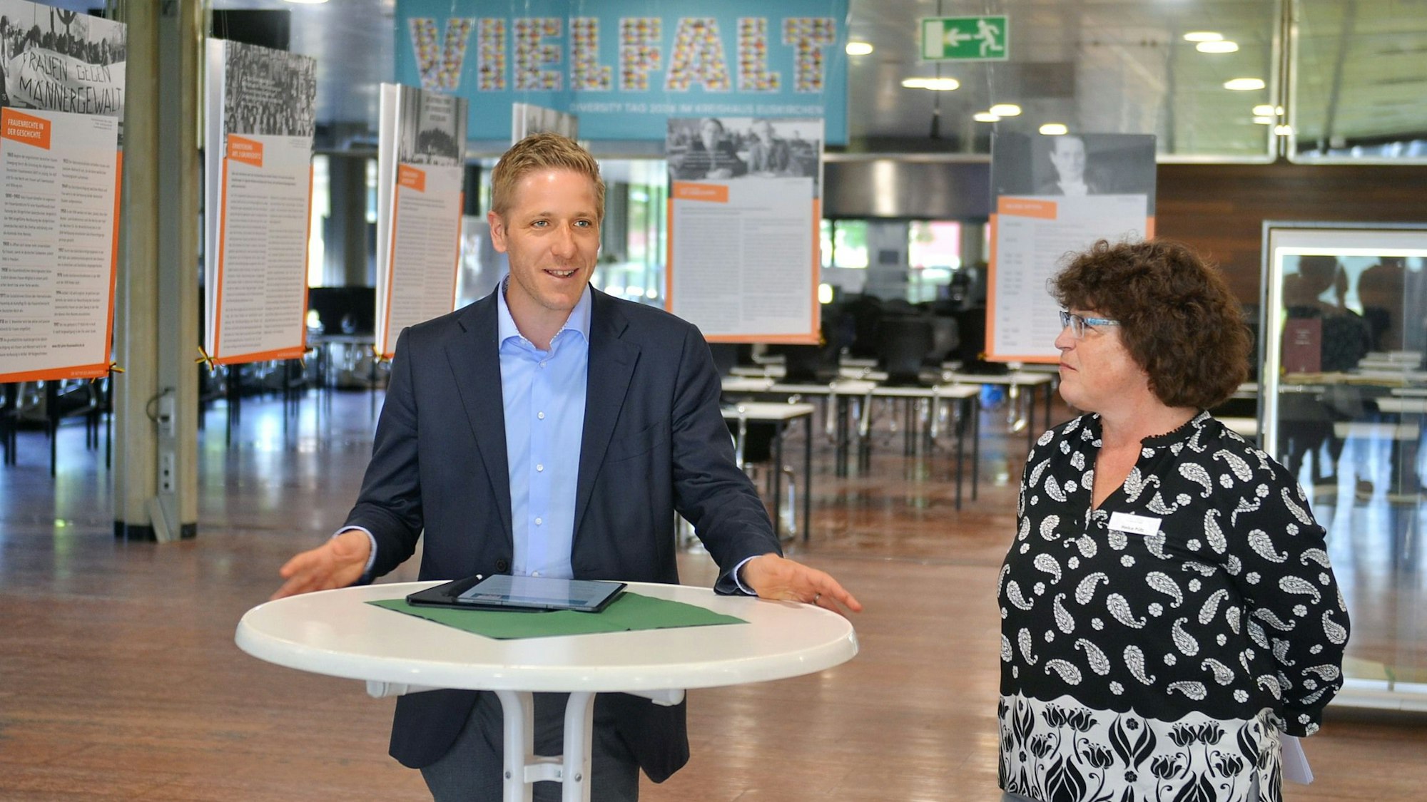 Landrat Markus Ramers und Kreisarchivarin Heike Pütz stehen nebeneinander an einem Stehtisch vor einer Ausstellung.