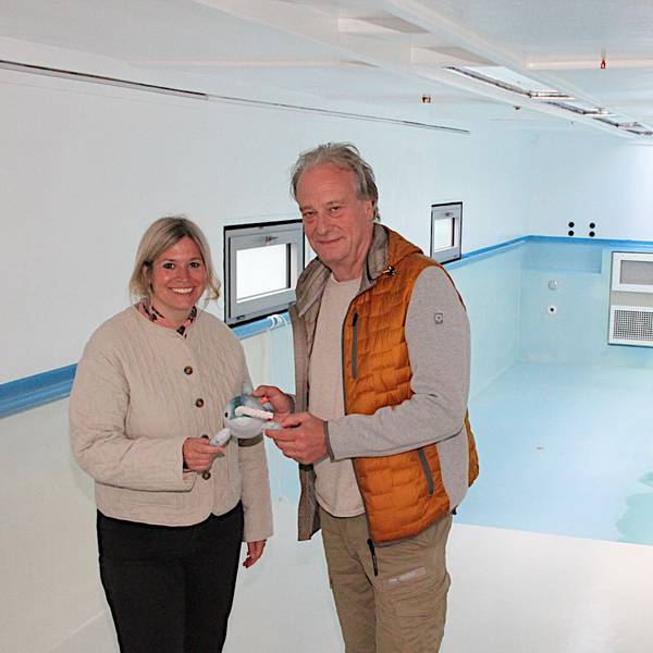 Wolfgang Schmitz vom Kreissportbund Düren und Blankenheims Bürgermeisterin Jennifer Meuren stehen im Schwimmbad-Container. Sie halten das Narwali-Maskottchen in der Hand.
