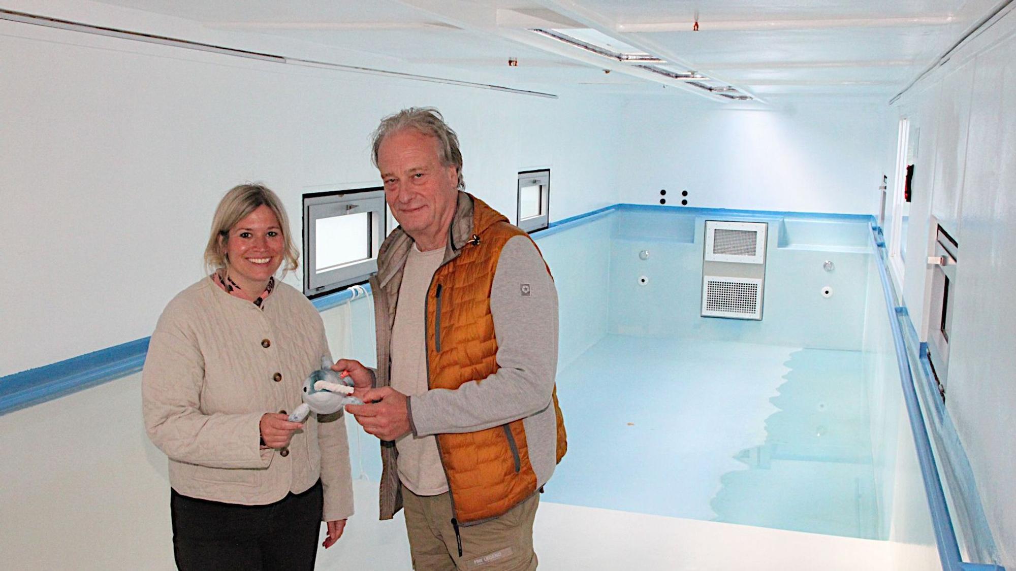 Wolfgang Schmitz vom Kreissportbund Düren und Blankenheims Bürgermeisterin Jennifer Meuren stehen im Schwimmbad-Container. Sie halten das Narwali-Maskottchen in der Hand.