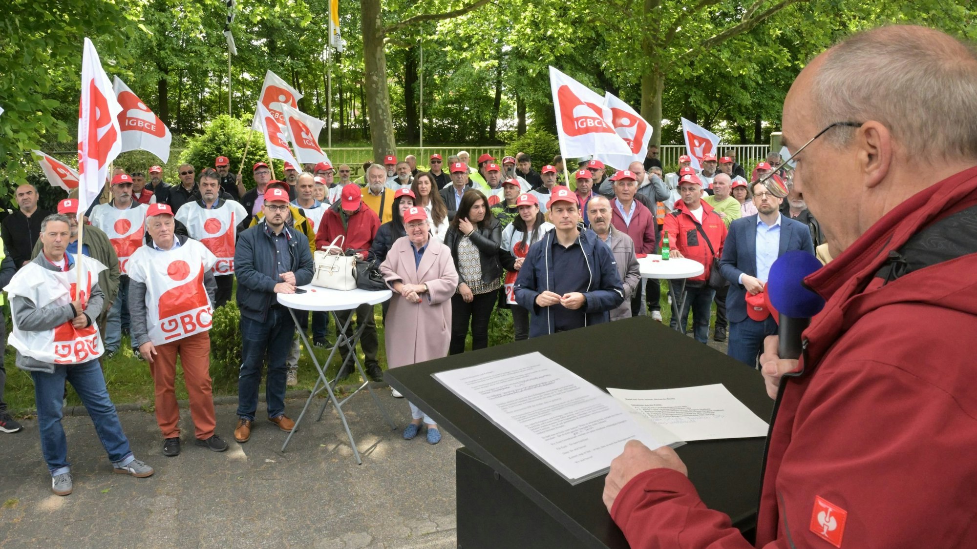 IGBCE-Gewerkschaftssekretär Thomas John Dyer spricht vor dem Werkstor von Isover in Bergisch Gladbach zu Protestierenden.