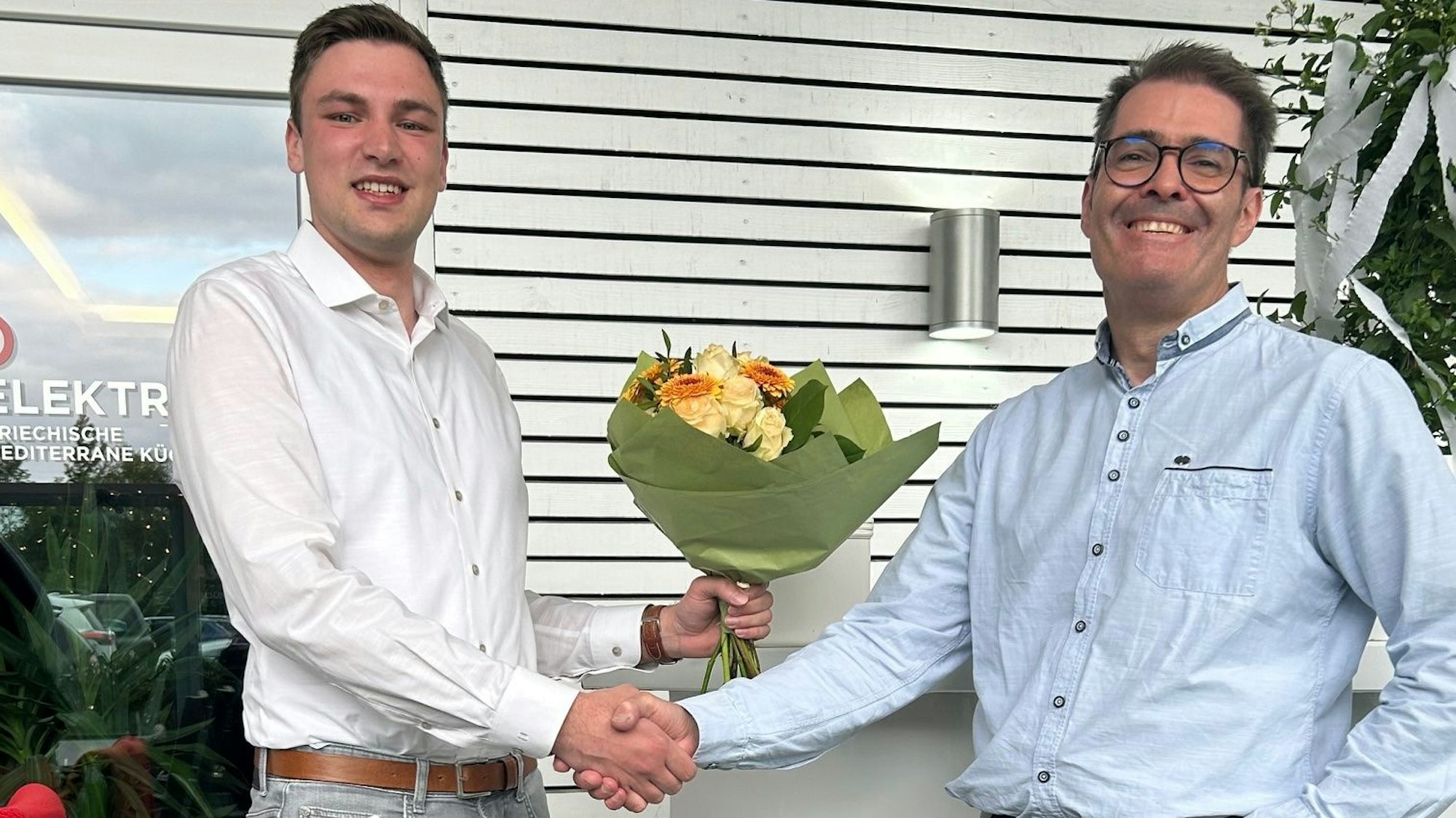 Lukas Krüger (l.) schüttelt die Hand von Oliver Totter und überreicht ihm einen Blumenstrauß.