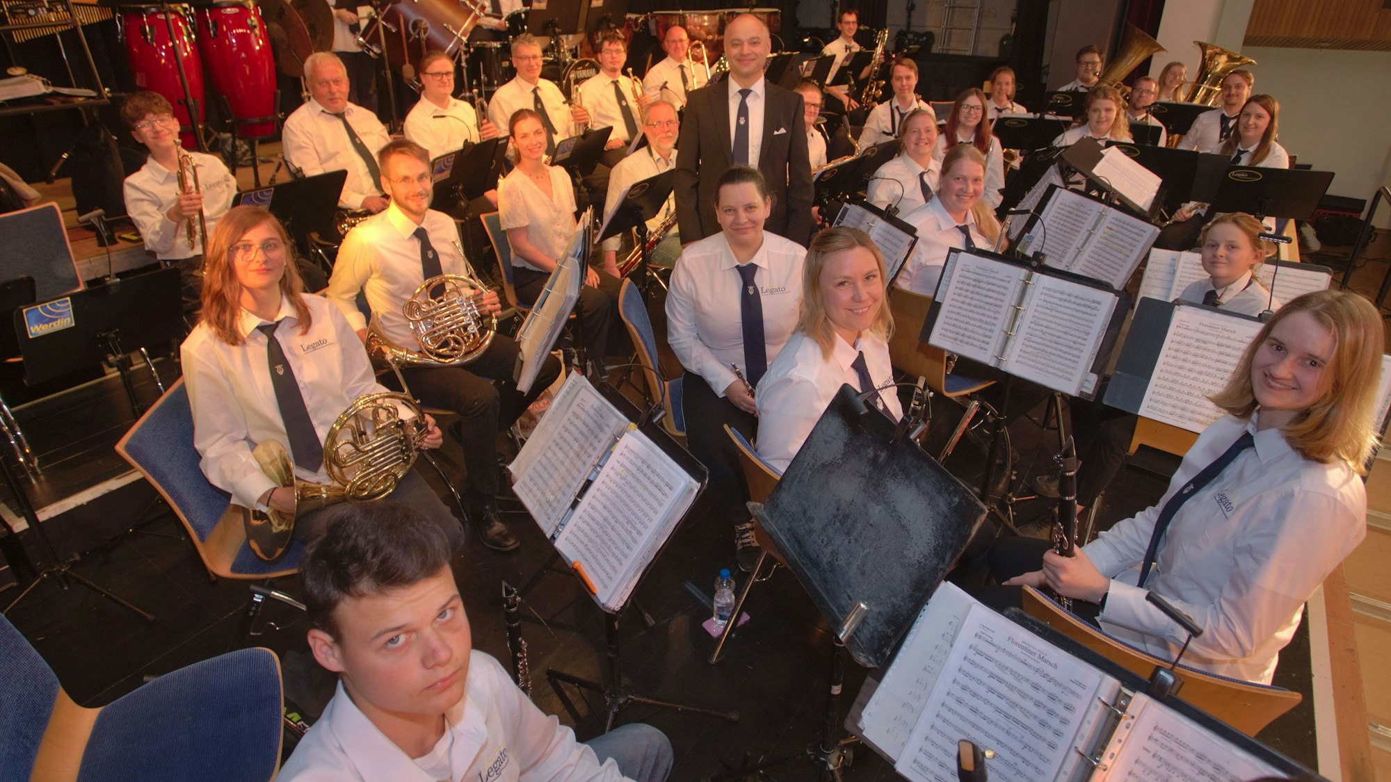 Ein Dirigent steht inmitten eines Orchesters.