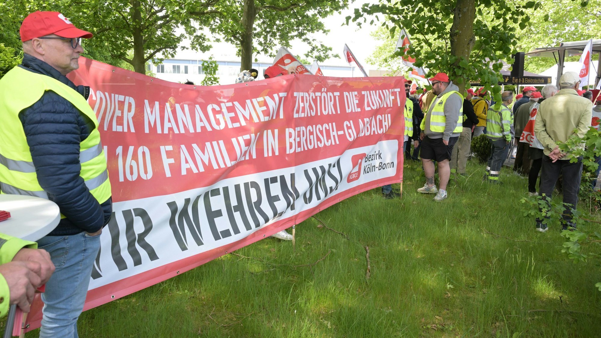 Demonstrierende halten beim „Aktionstag“ vor dem Isover-Standort in Bergisch Gladbach ein Transparent in den Händen, auf dem unter anderem steht: „Isover Management zerstört die Zukunft von 160 Familien in Bergisch Gladbach.“