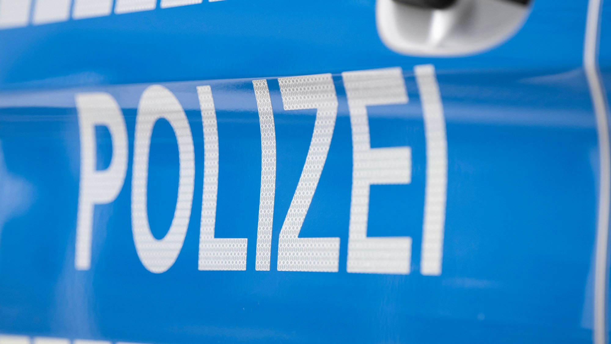 Das Foto zeigt den Schriftzug „Polizei“ auf einem Einsatzwagen.