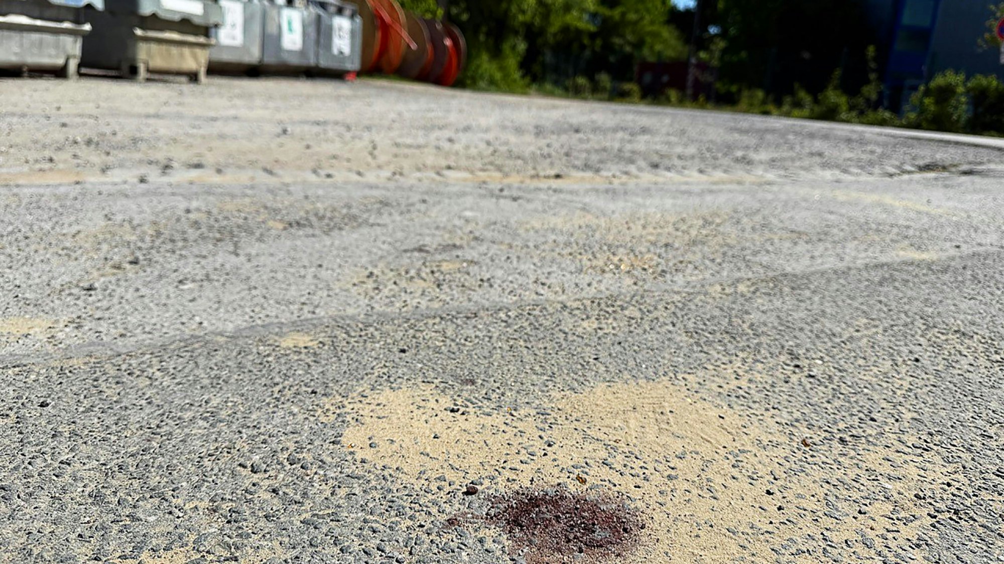 Ein Blutfleck ist auf dem Asphalt am Tatort in Menden im Sauerland zu sehen. Nach dem gewaltsamen Tod eines 14-Jährigen ermittelt die Polizei.