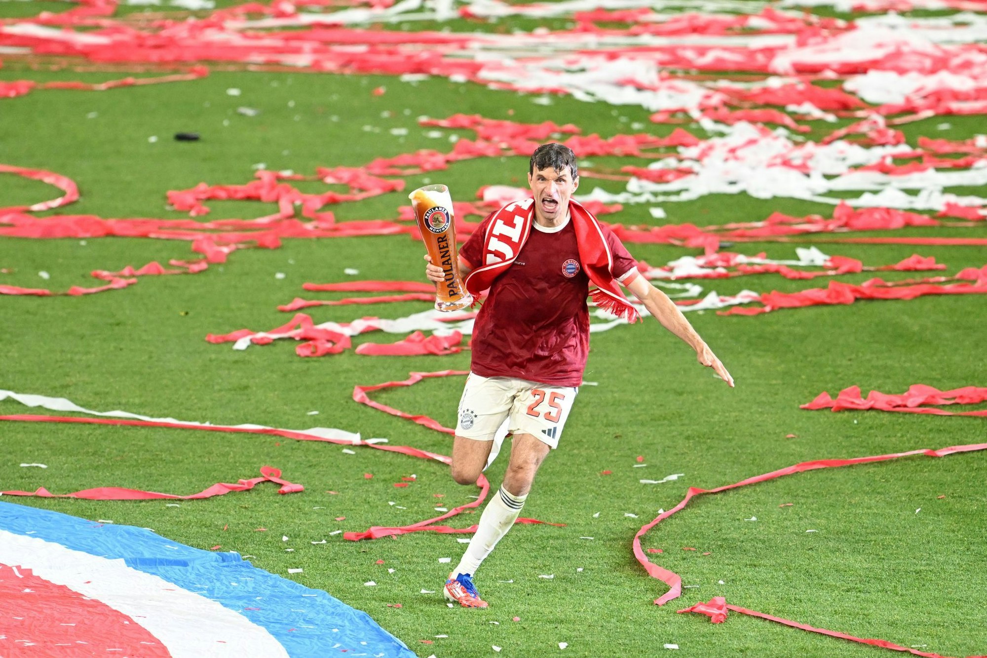 Thomas Müller rennt bei der Meisterfeier mit Bier über das Feld.