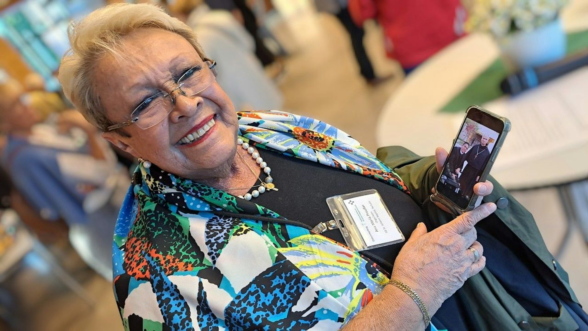 Ana Maria Preußer schaut von ihrem Handy auf, auf dem ein Foto des neuen Papstes als Augustinermönch zu sehen ist.