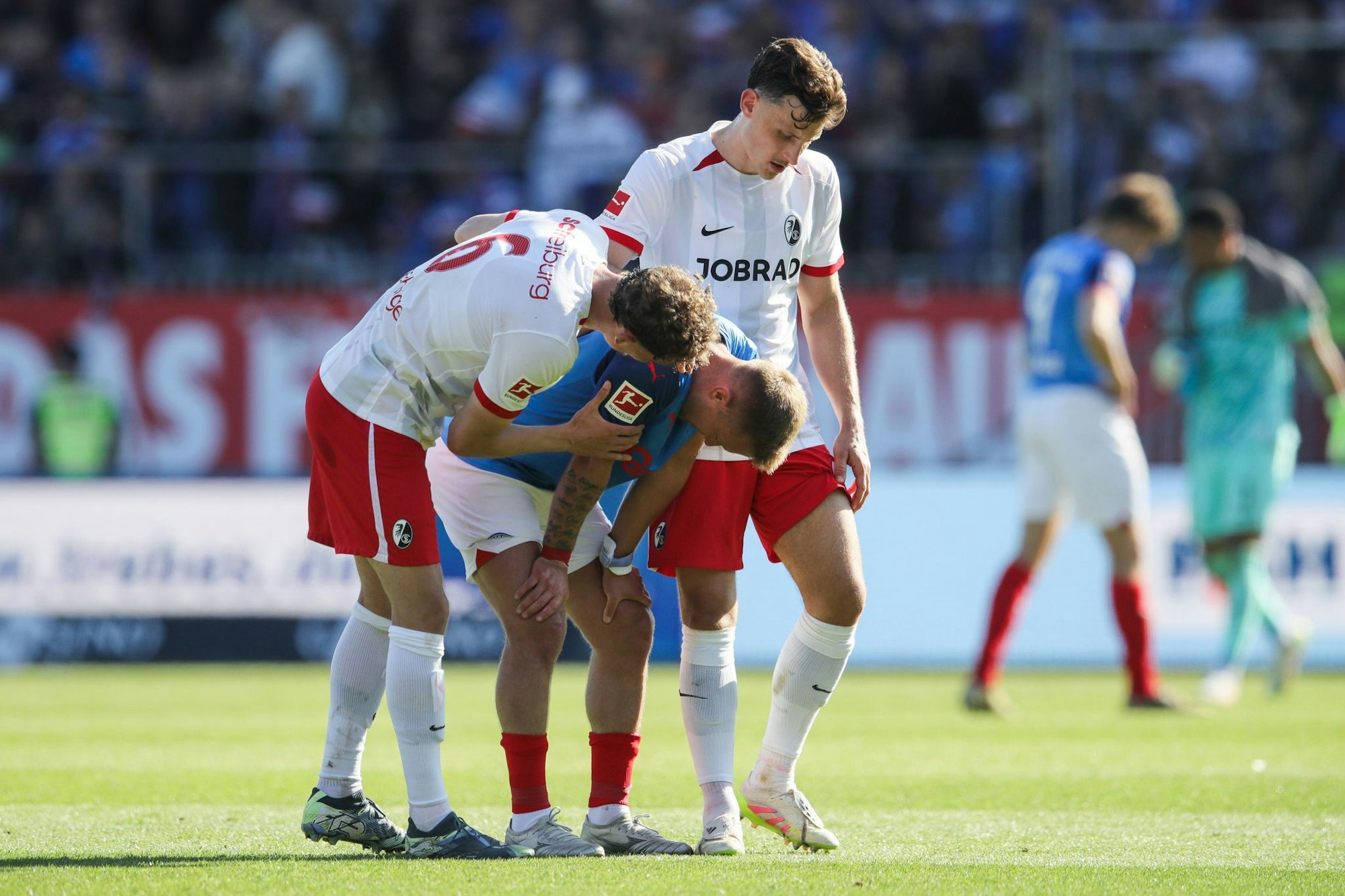 Kiels Lewis Holtby wird nach dem Abstieg von den Freiburgern Patrick Osterhage (l) und Maximilian Eggestein getröstet.