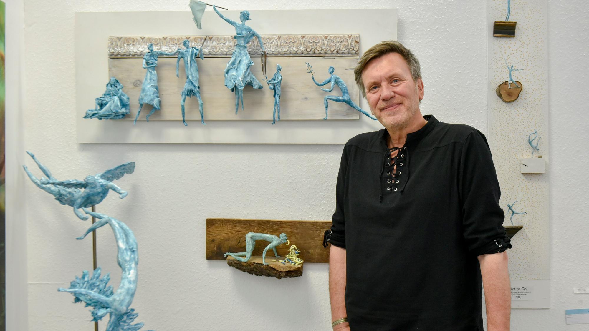 Andre Duront steht vor seinen Skulptren, die dank Magneten an der Wand hängen.