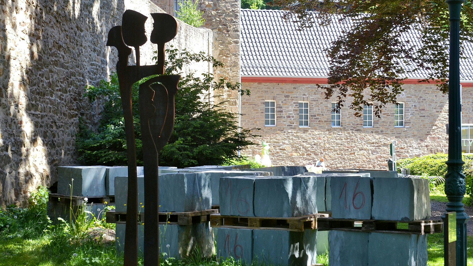 Eine Metallstele steht inmitten von Steinblöcken an der Stadtmauer in Bad Münstereifel.