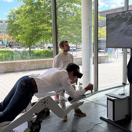 Ein Besucher liegt auf dem Flugsimulator und trägt eine VR-Brille.