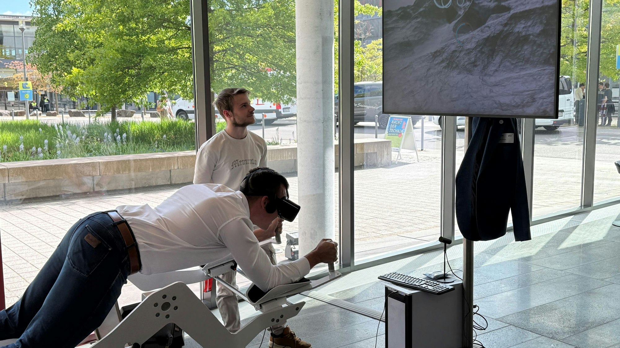 Ein Besucher liegt auf dem Flugsimulator und trägt eine VR-Brille.