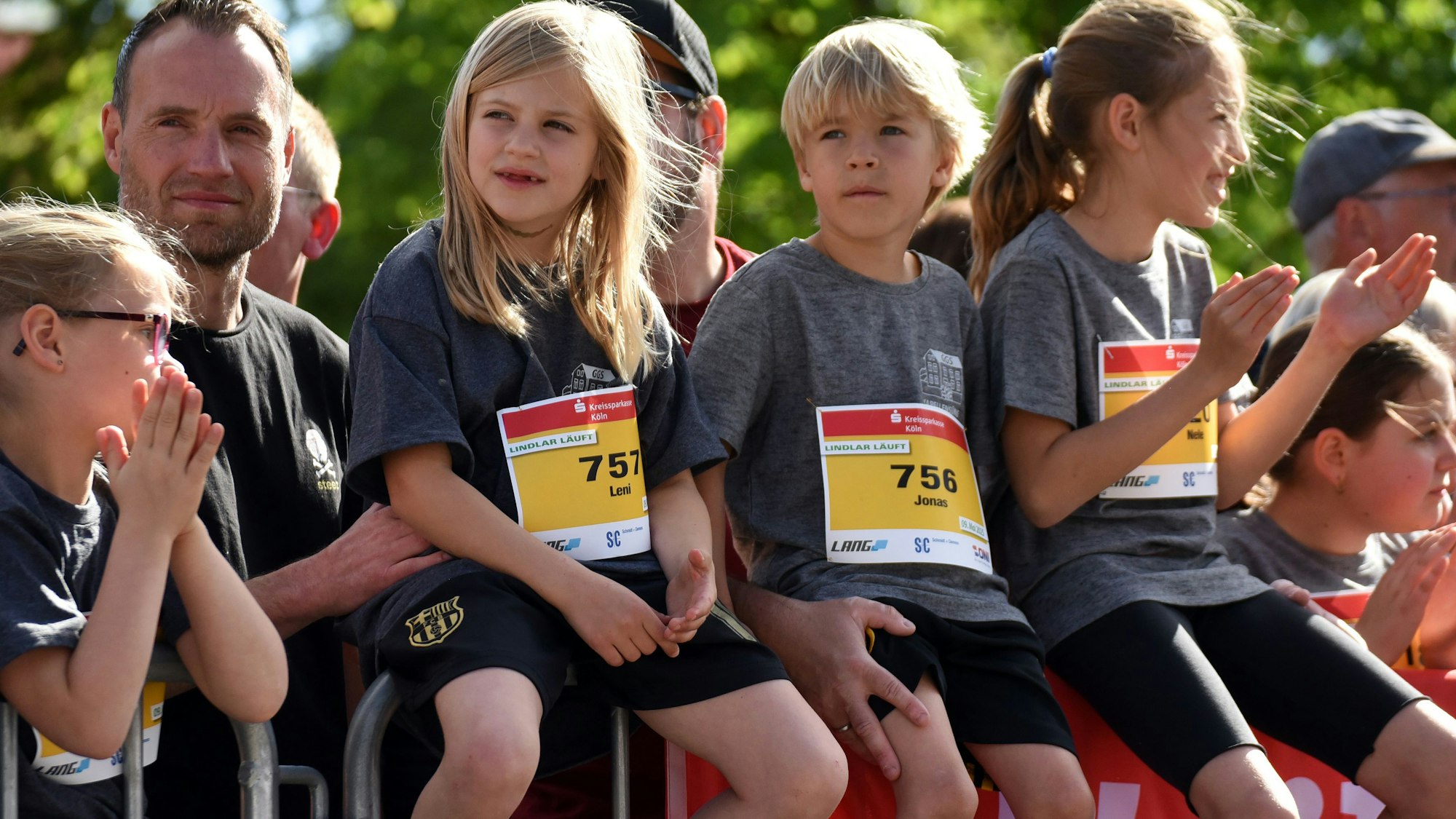 Drei junge Mädchen sitzen auf einem Absperrgitter.