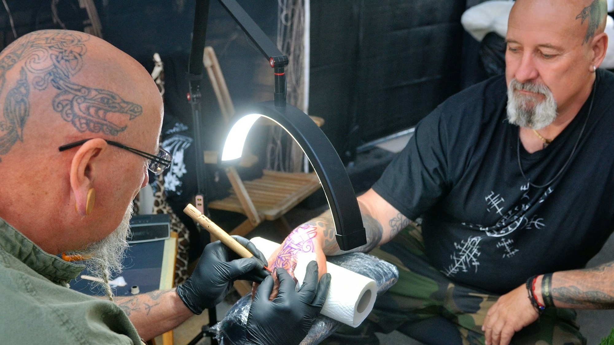 Eric Breker tätowiert den rechten Handrücken seines Stammkunden Guido Bedbur.