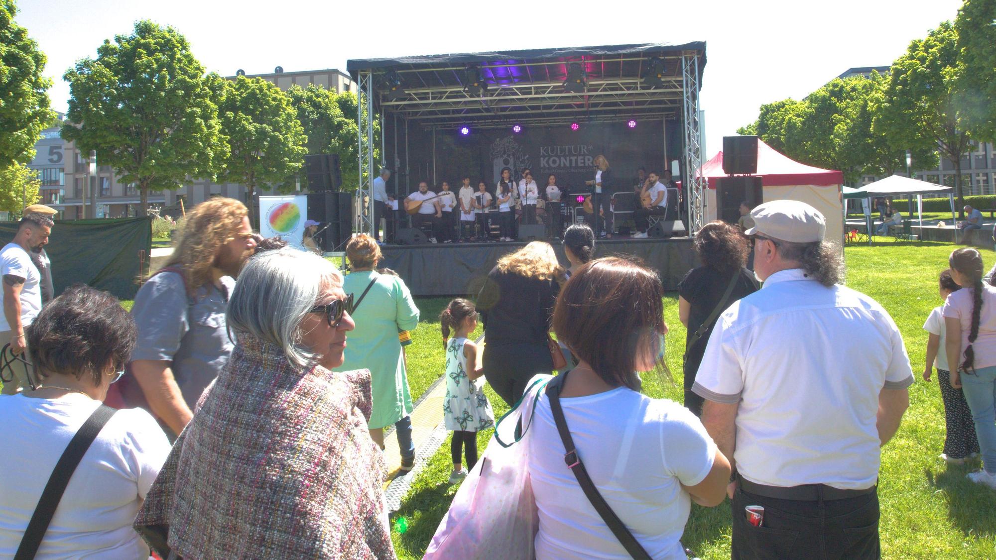 Vor der aufgebauten Bühne im Gummersbacher Stadtgarten, hören Besucher des Festivals dem Chor der anatolischen Stimme zu.