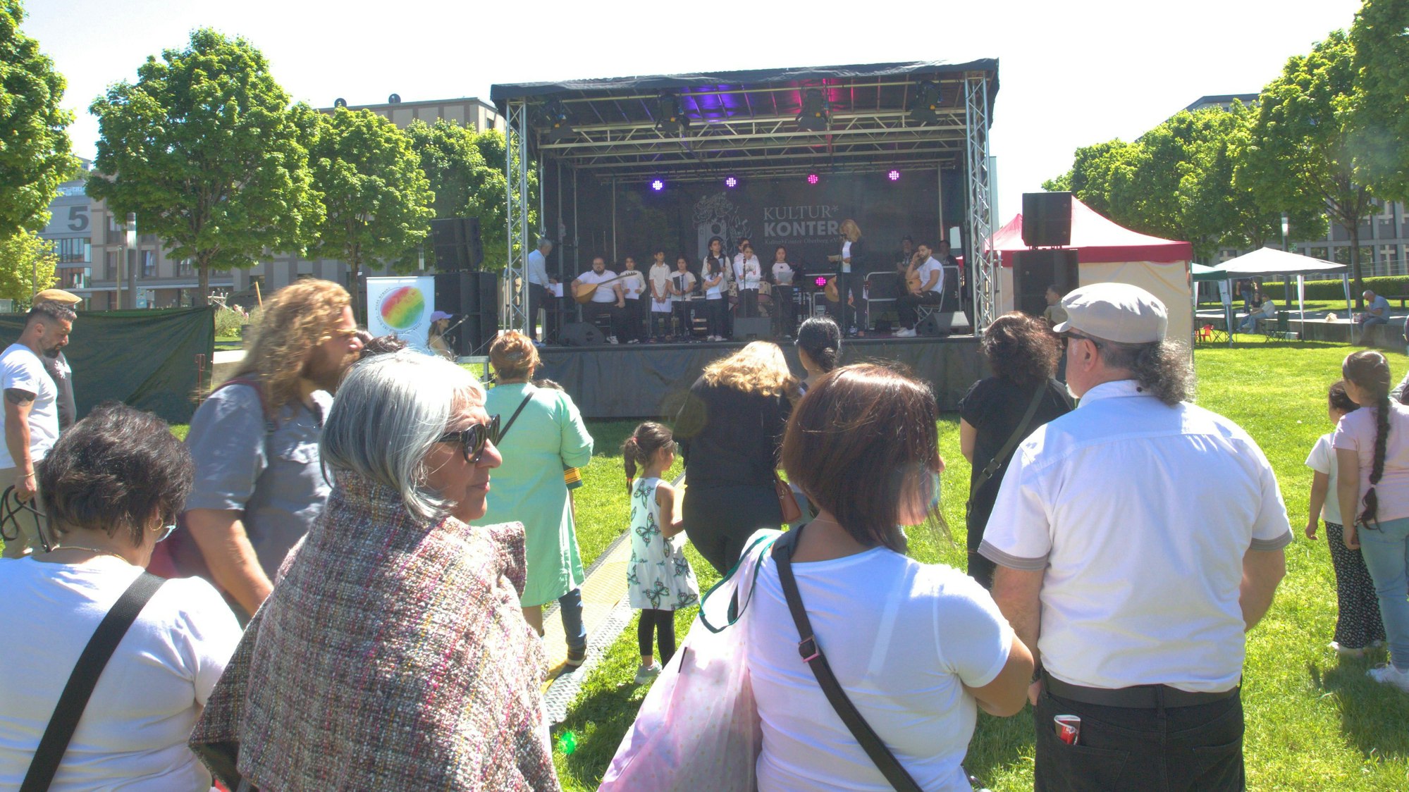Vor der aufgebauten Bühne im Gummersbacher Stadtgarten, hören Besucher des Festivals dem Chor der anatolischen Stimme zu.