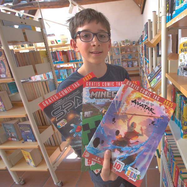 Ein Junge hält mehrere Comics in den Händen.