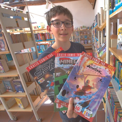 Ein Junge hält mehrere Comics in den Händen.
