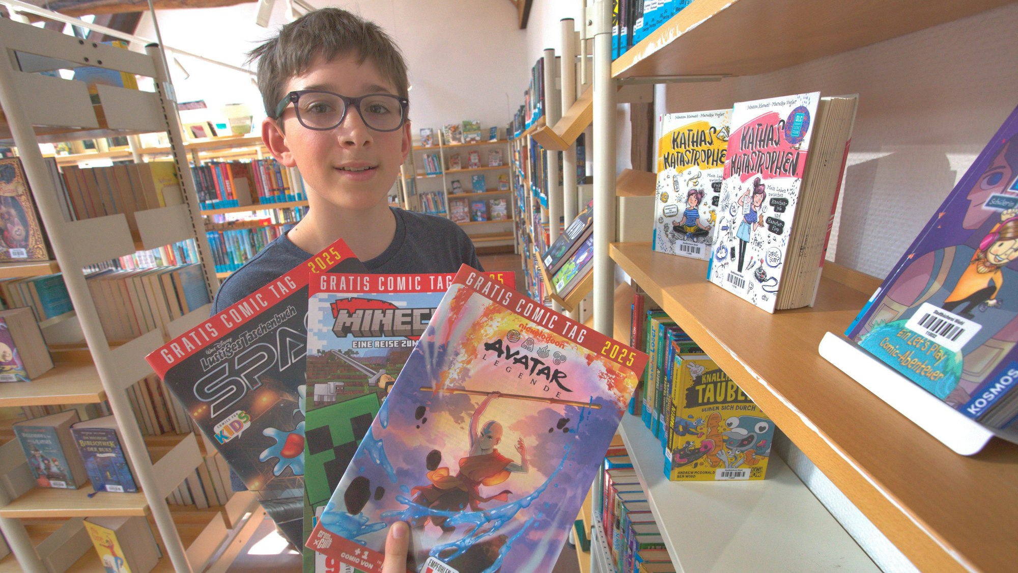 Ein Junge hält mehrere Comics in den Händen.