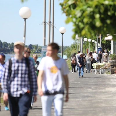 Menschen flanieren an einem Sommertag auf der Rheinpromenade in Königswinter.
