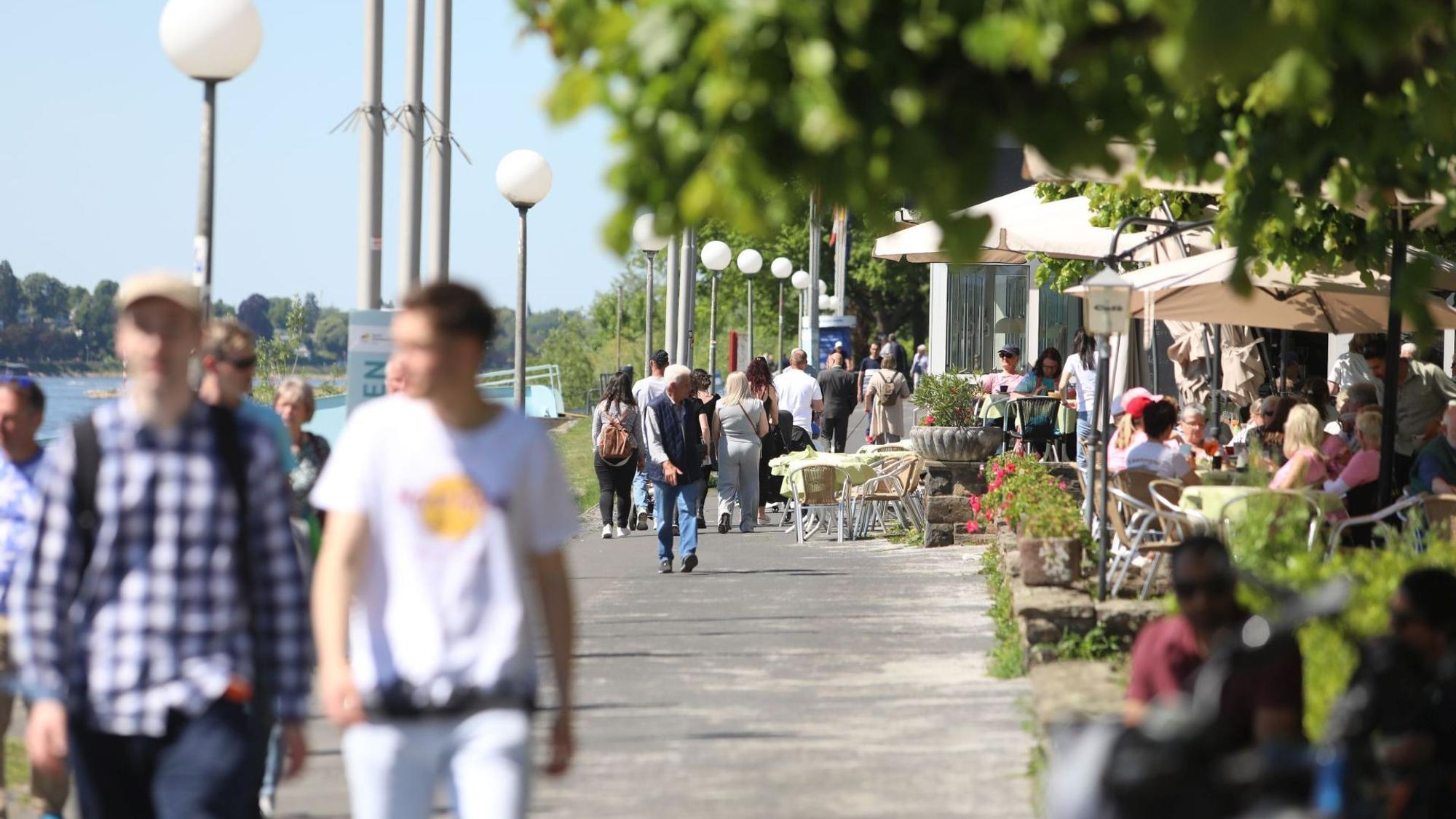 Menschen flanieren an einem Sommertag auf der Rheinpromenade in Königswinter.