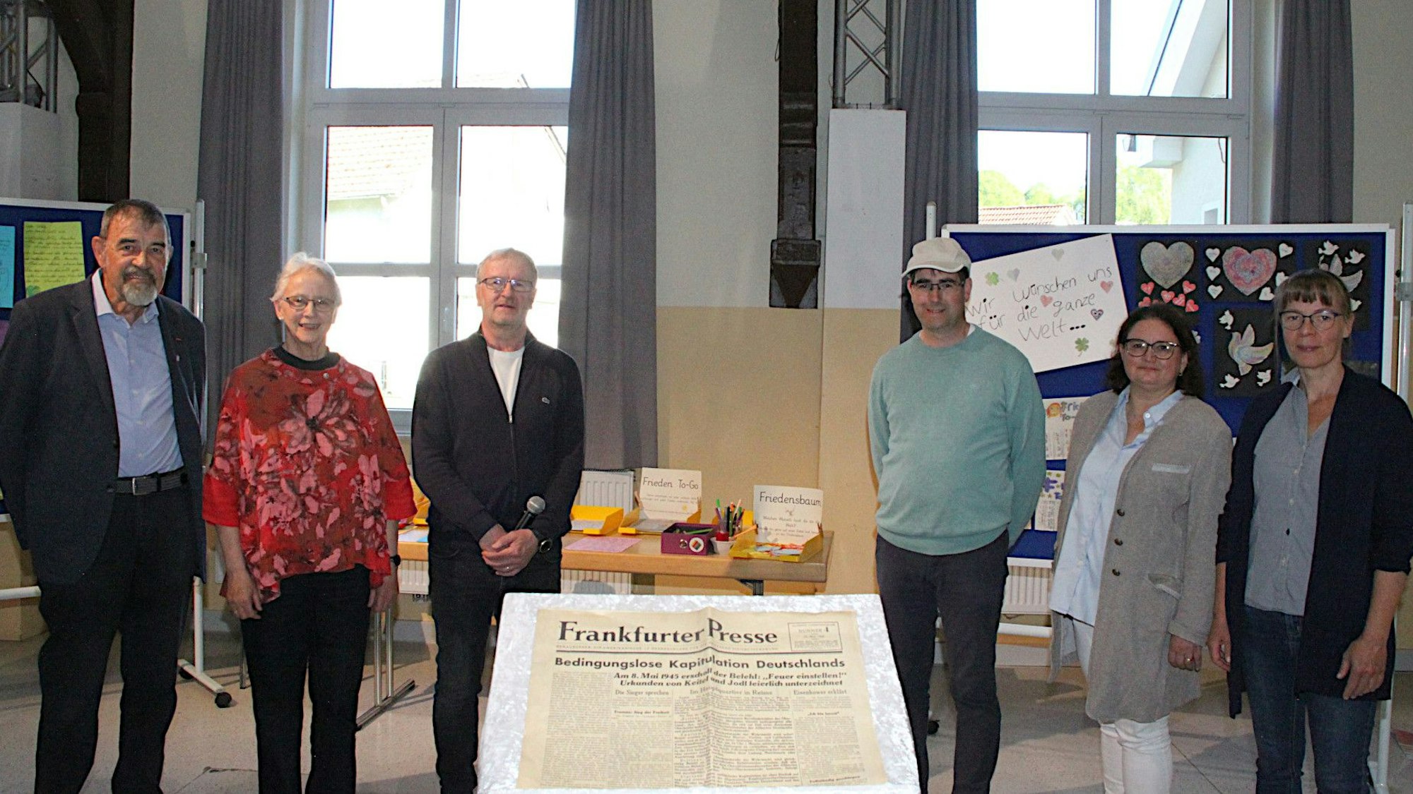 Die Organisatoren der Ausstellung im Dahlemer Vereinshaus hinter einem Exemplar der „Frankfurter Presse“ vom 10. Mai 1945 mit der Schlagzeile: „Bedingungslose Kapitulation Deutschlands“.