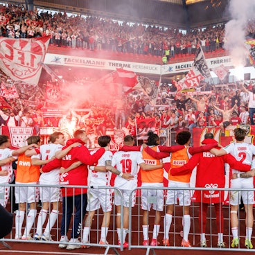 Kölner Zusammenhalt: Die FC-Spieler stehen nach dem 2:1 in Nürnberg Arm in Arm vor der Fankurve.