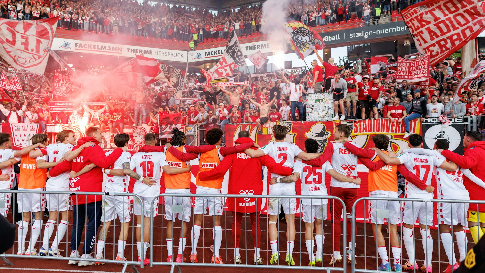 Kölner Zusammenhalt: Die FC-Spieler stehen nach dem 2:1 in Nürnberg Arm in Arm vor der Fankurve.