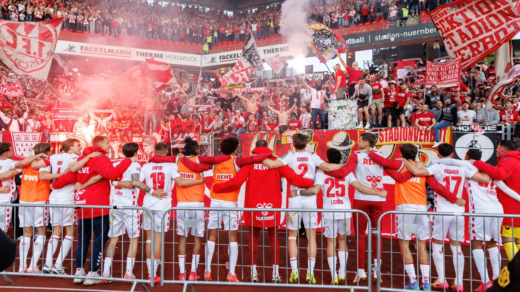 Kölner Zusammenhalt: Die FC-Spieler stehen nach dem 2:1 in Nürnberg Arm in Arm vor der Fankurve.