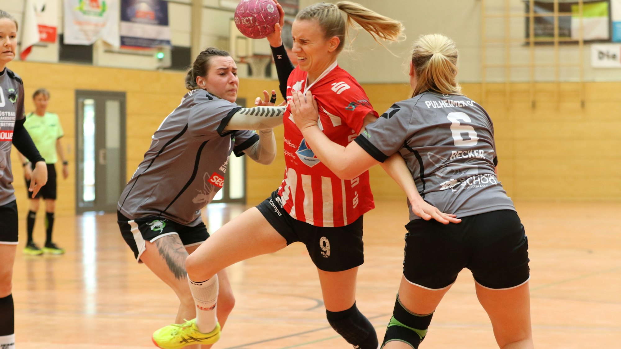 Corinna Schmitz wird beim Wurf von zwei Gegnerinnen attackiert und verzieht das Gesicht.