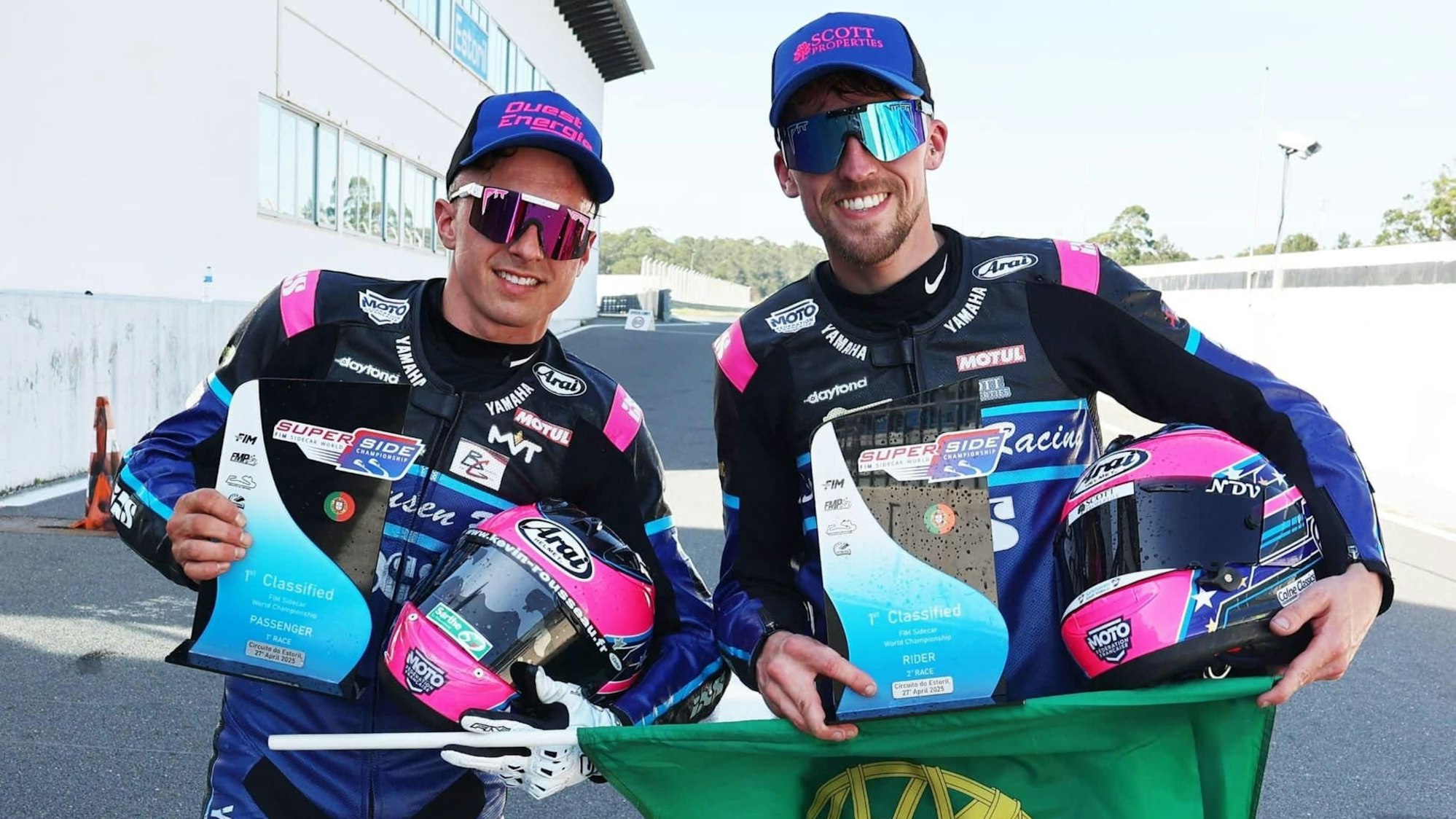 Foto von zwei Motorradrennfahrern, die Pokale in den Händen halten.