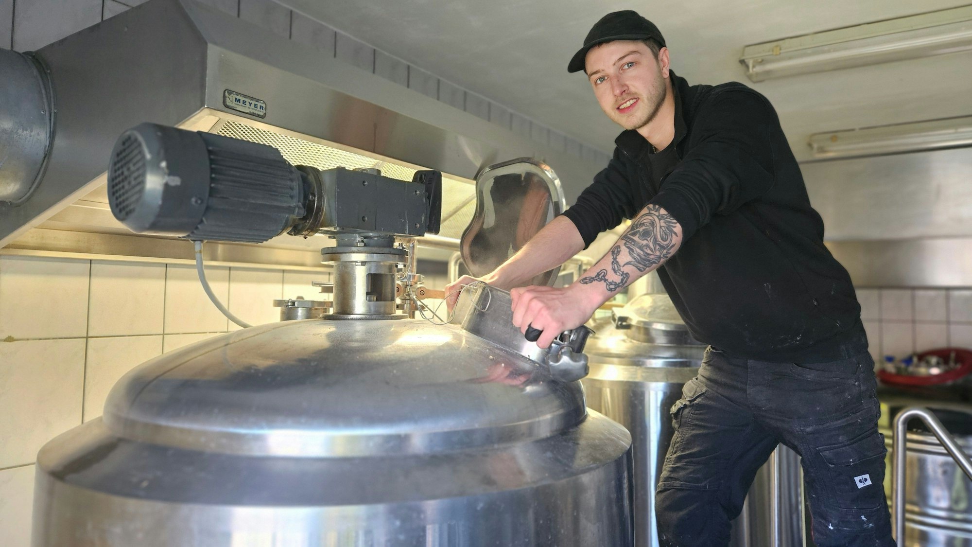 Braumeister Till Verse steht an einem Bottich aus Edelstahl.