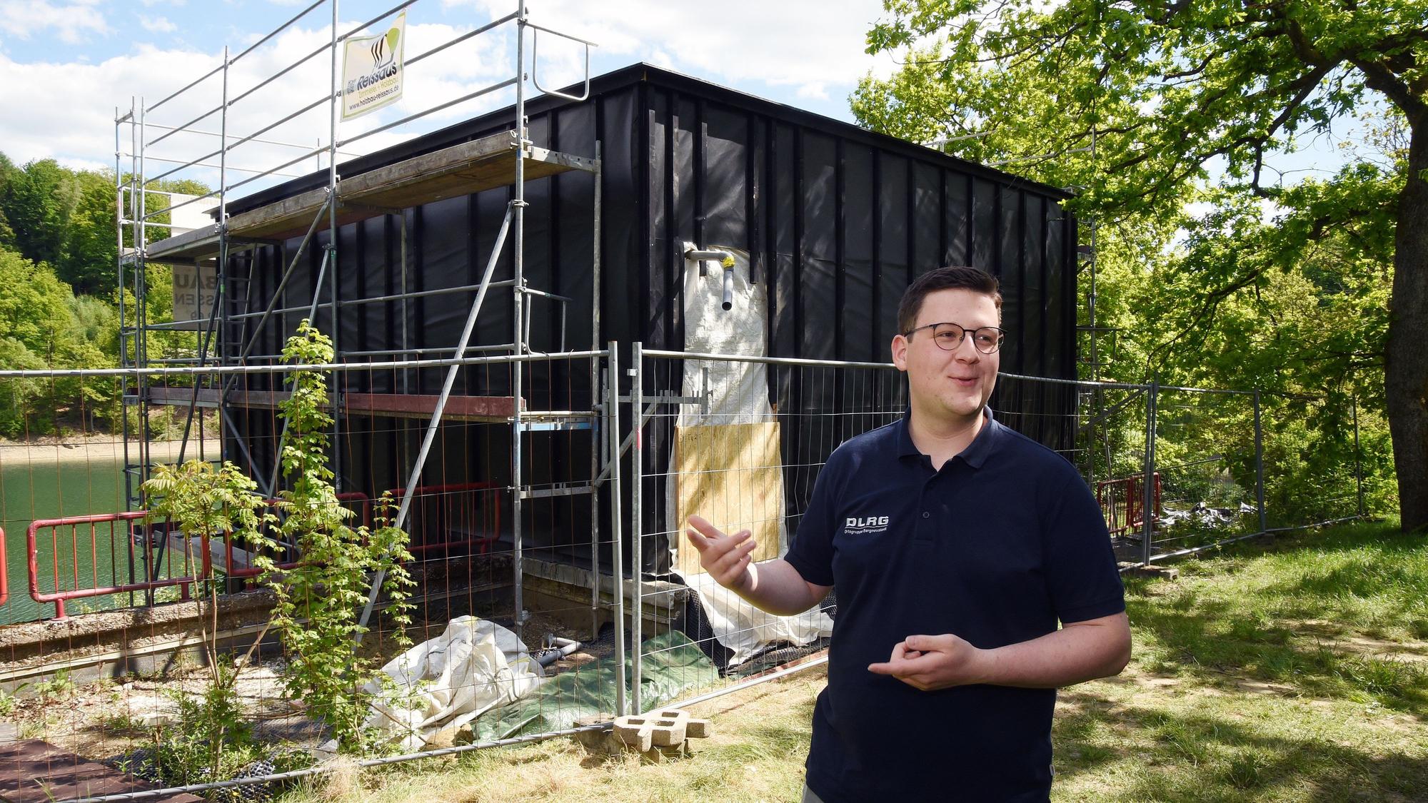 Ein Mann steht vor dem Neubau einer neuen Wasserrettungsstation.