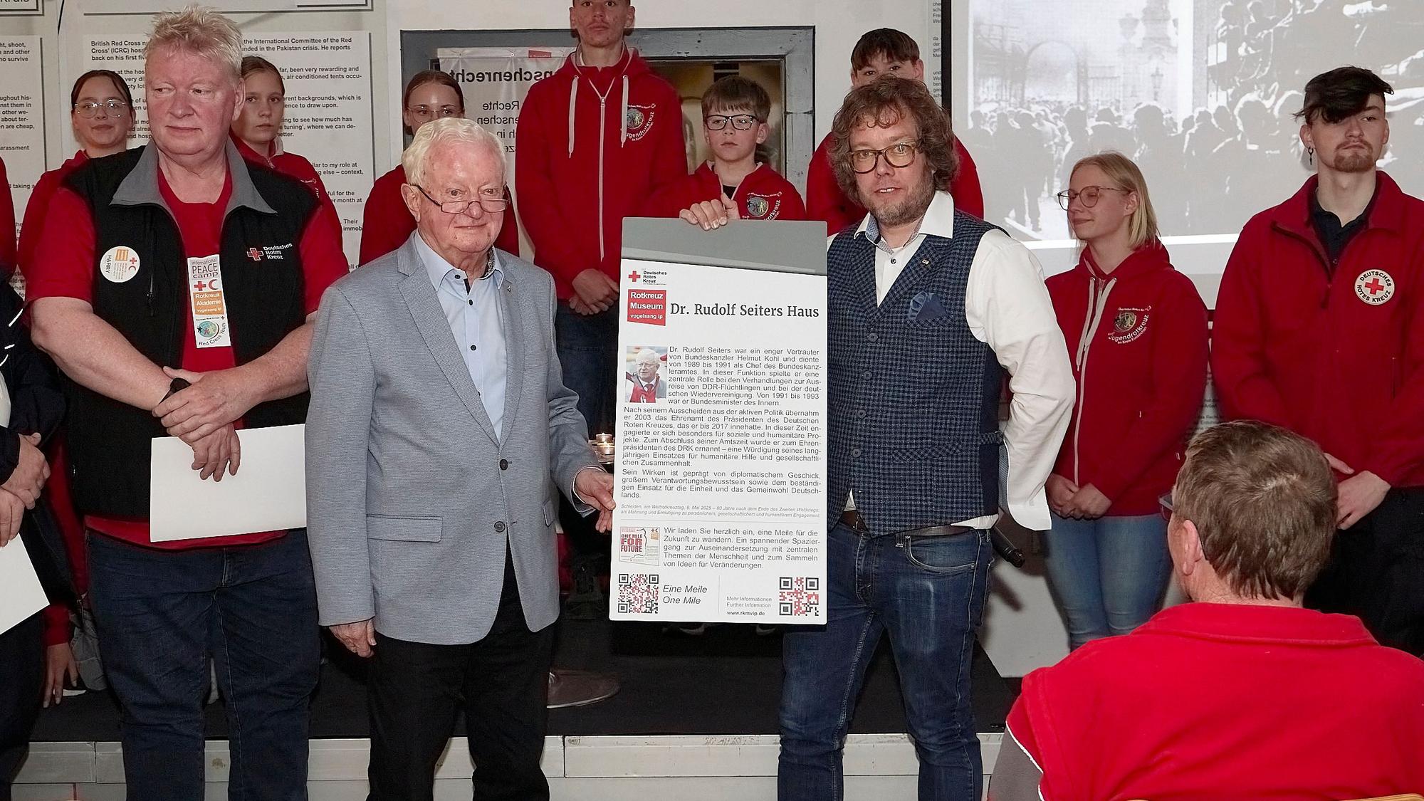 Simon Jägersküpper und Namenspate Dr. Rudolf Seiters halten ein Schild mit dem Namen Dr.-Rudolf-Seiters-Haus in den Händen.