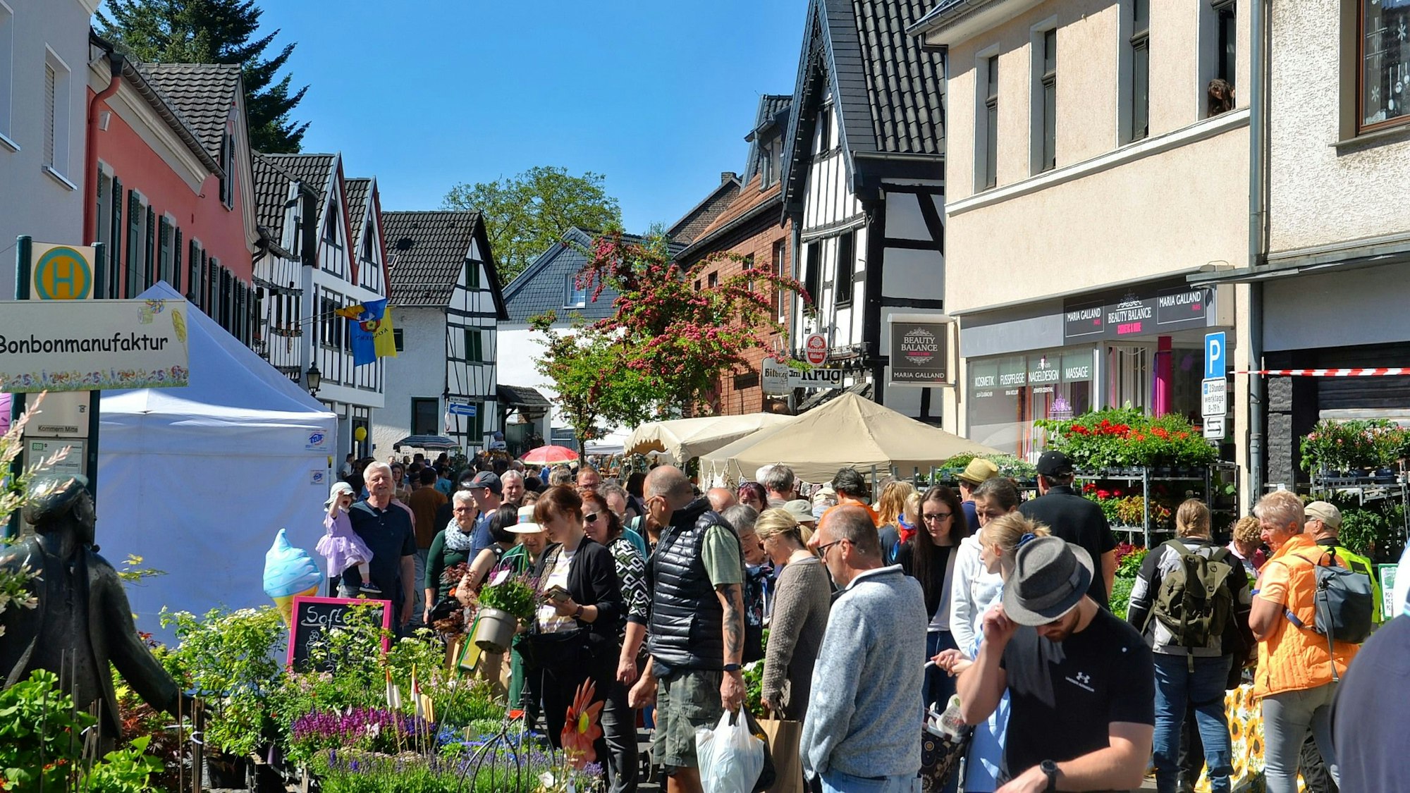 Menschenmassen schlendern entlang der Fachwerkhäuser in Kommern und schauen sich die Marktwaren an.