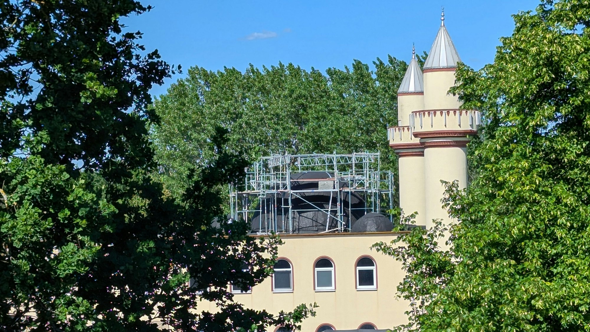 Das Foto zeigt die Moschee in Alt-Hürth mit der eingerüsteten Kuppel und den beiden Minaretten.