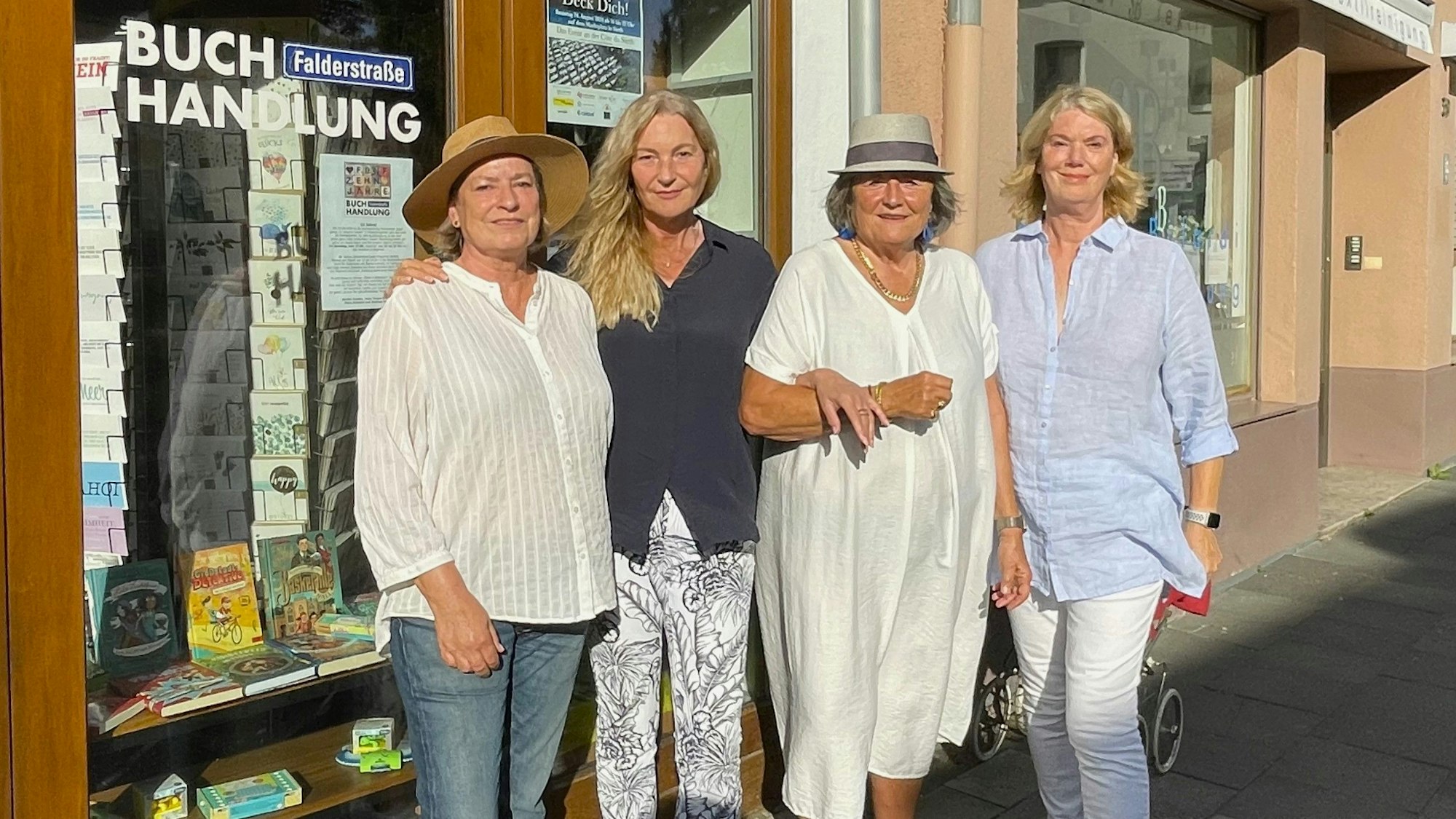 Vier Frauen stehen bei strahlendem Sonnenschein vor dem Schaufenster eines Buchladens.