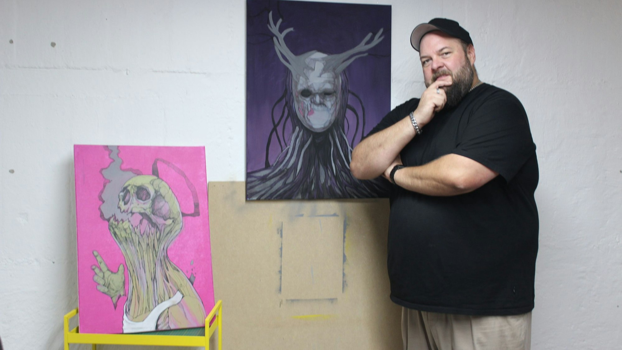 Auf dem Bild ist der Künstler Oliver Bendlin mit zwei seiner Werke zu sehen.