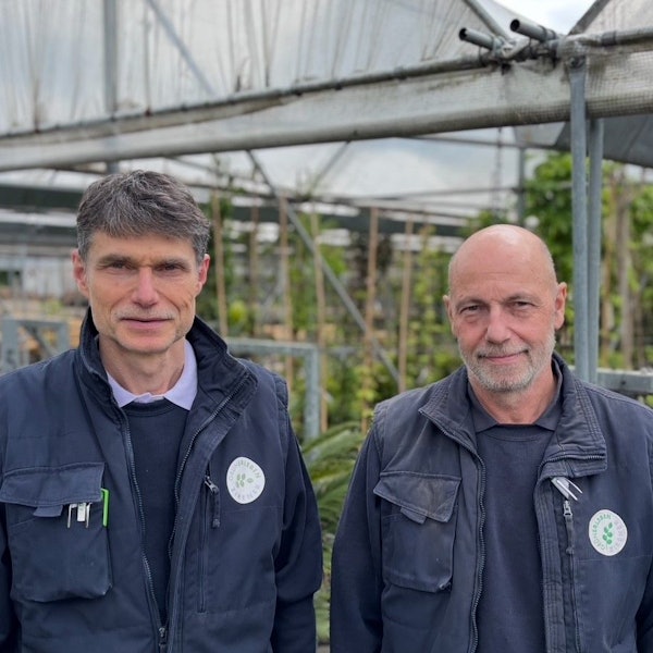 Auf dem Bild sind zwei Männer in Arbeitskleidung, Frank und Ralf Zirener, vor fast leer geräumten Gewächshäusern zu sehen.