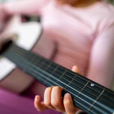 Das Symbolfoto zeigt ein Kind, das Gitarre spielt.