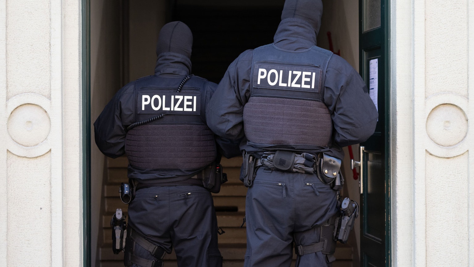 Polizisten stehen während einer Razzia gegen mutmaßliche Rechtsextreme in einem Hauseingang im Dresdner Stadtteil Cotta. (Archivbild)