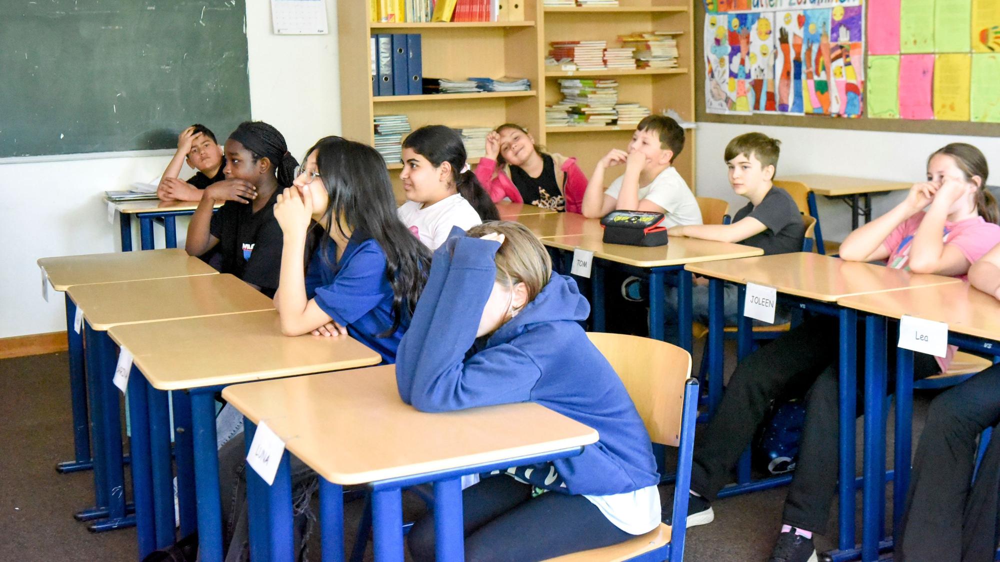 Auf dem Bild sind Schulkinder an Tischen in ihrem Klassenzimmer zu sehen.