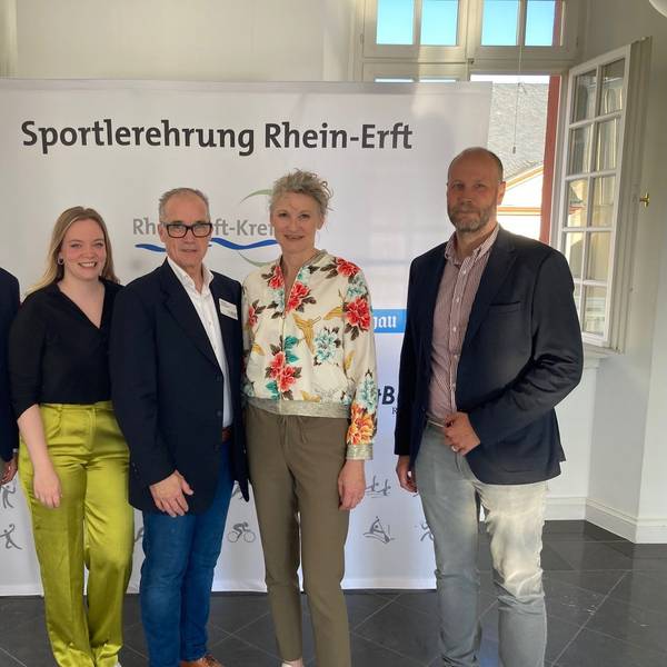 Männer und Frauen stehen vor einem Banner, auf dem „Sportlerehrung Rhein-Erft“ steht.