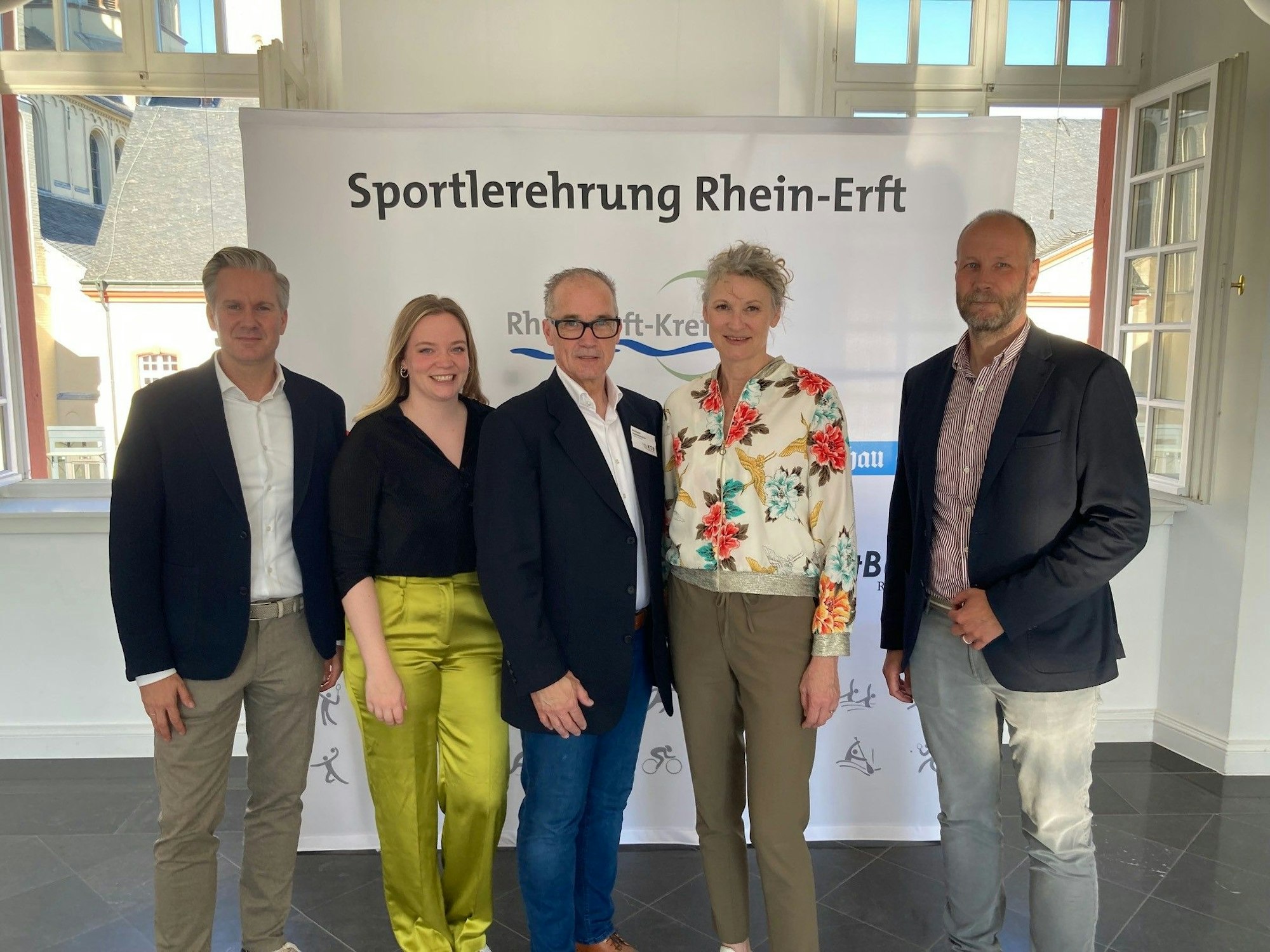 Männer und Frauen stehen vor einem Banner, auf dem „Sportlerehrung Rhein-Erft“ steht.