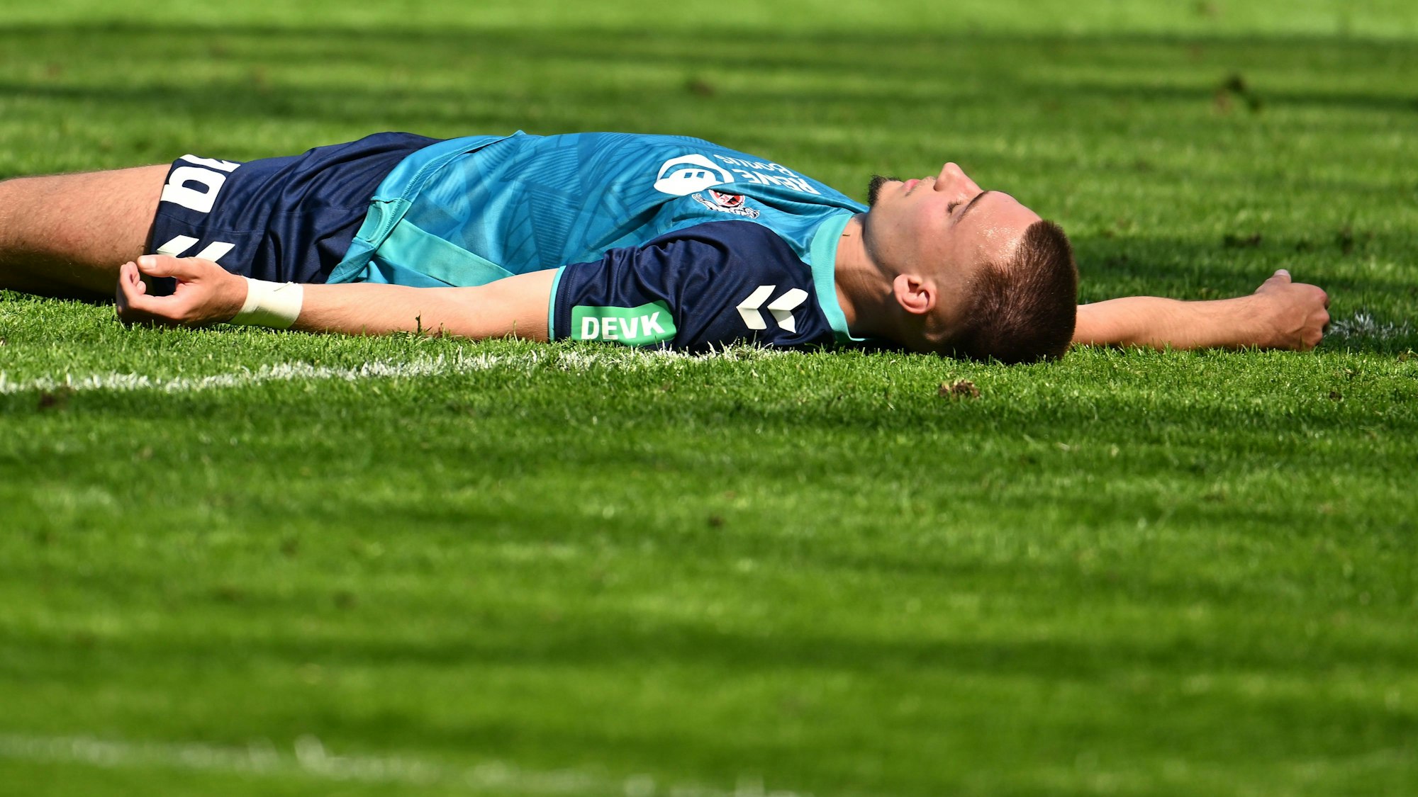 Tim Lemperle liegt erschöpft auf dem Rasen.
