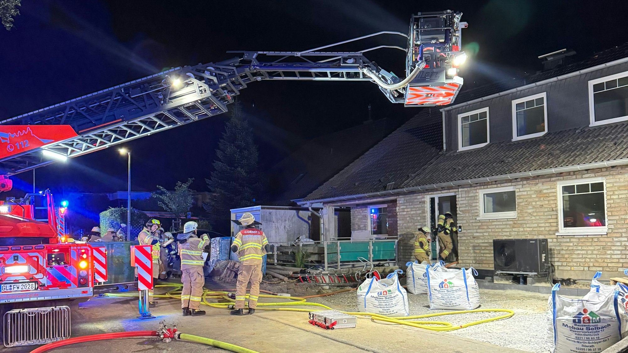 Eine Drehleiter der Feuerwehr Bergisch Gladbach steht an einem Haus im Alten Traßweg in Bergisch Gladbach-Kippekausen. Feuerwehrleute stehen davor.